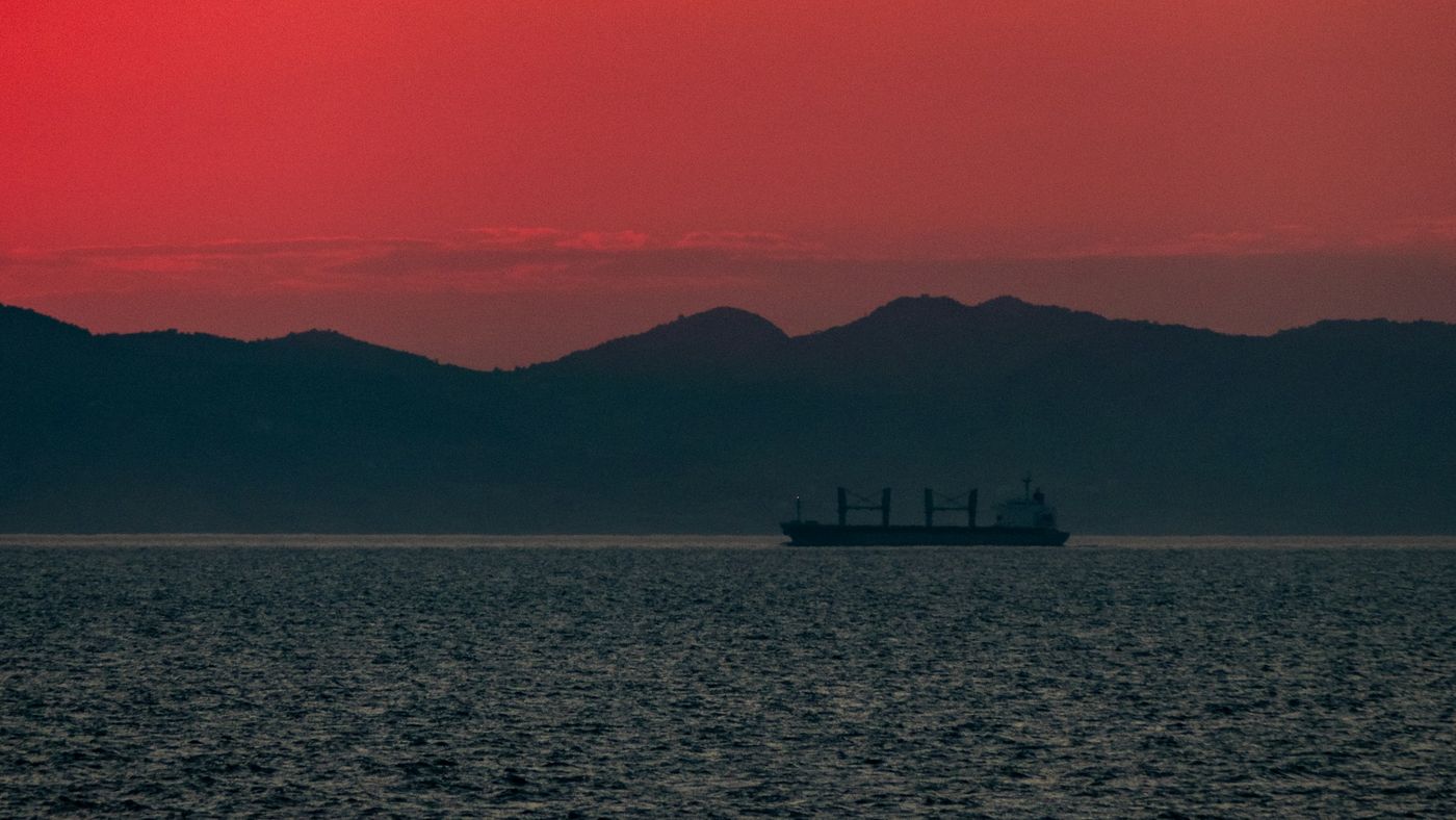 Cargo ship silhouetted against a red sunset