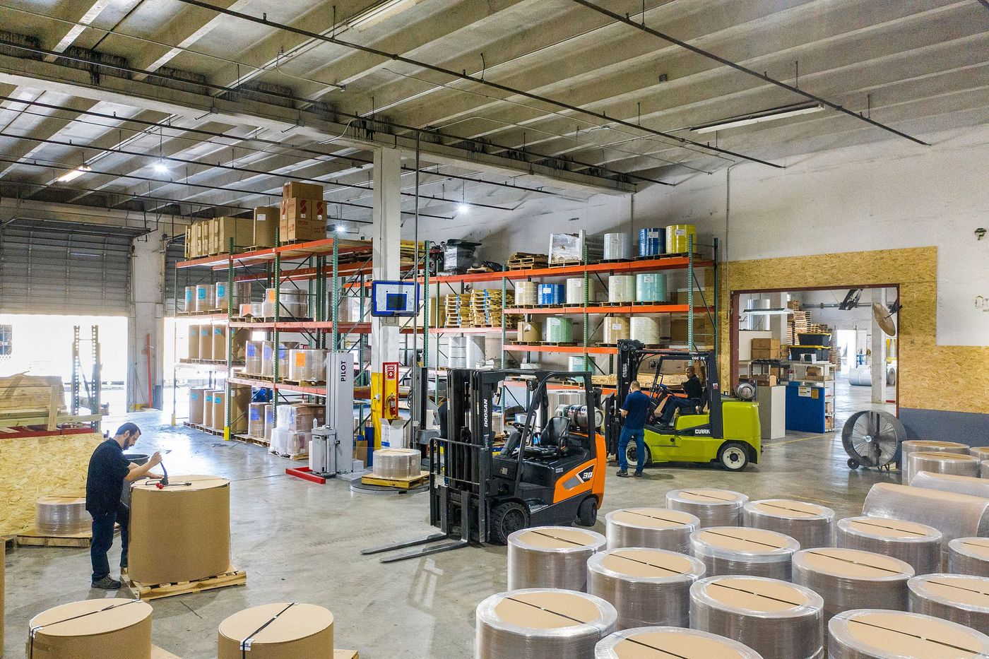 Large paper reels being moved by forklift inside a warehouse